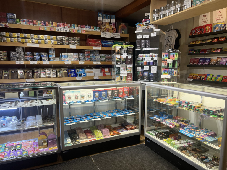 Oka smoke shop interior with tobacco, vape, cannabis edibles, and psychedelic products displayed in glass cases and wall shel